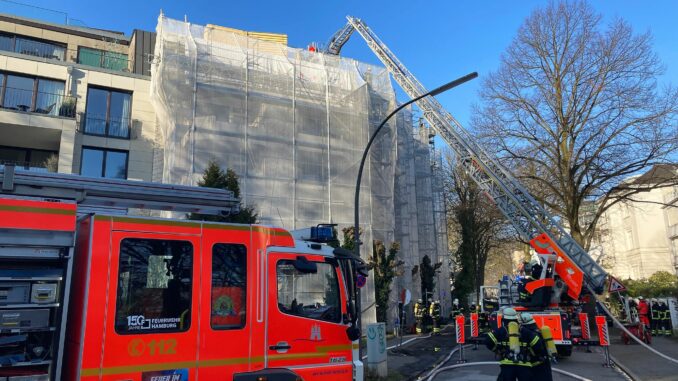 Brand auf Baustelle in Hamburg-Rotherbaum Über eine Drehleiter löschen Feuerwehrleute Glutnester auf dem Dach einer Baustelle ab.
