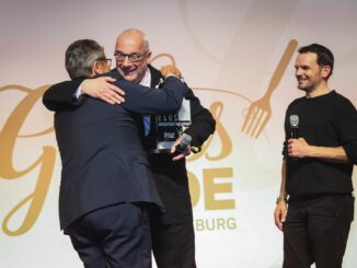 Rainer Sass (M), Moderator und Fernsehkoch, Sigmar Gabriel (SPD, l), Bundesaußenminister a.D., und Stefen Henssler, Gastronom und Fernsehkoch, stehen bei der Verleihung des Gastropreises "Genuss-Michel 2025" in den Fischauktionshallen auf der Bühne.