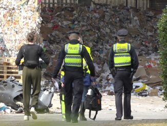 Einsatzkräfte der Polizei ermitteln auf dem Gelände einer Recyclingfirma, wo ein toter Mann gefunden wurde.