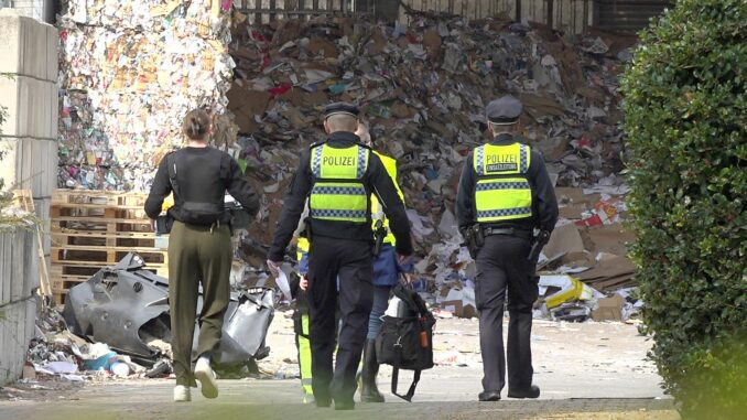Einsatzkräfte der Polizei ermitteln auf dem Gelände einer Recyclingfirma, wo ein toter Mann gefunden wurde. 