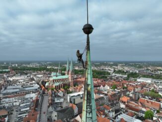 Ein Industriekletterer sichert Teile der kaputten Kupferverkleidung am Turm der Lübecker Jakobikirche.