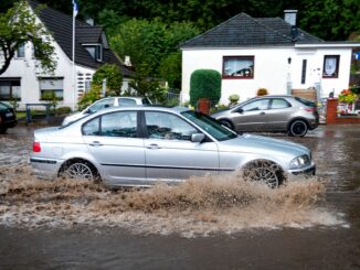 Ein Auto fährt im Hamburger Stadtteil Lohbrügge über eine von Starkregen überfluteten Straße. (Archivbild)