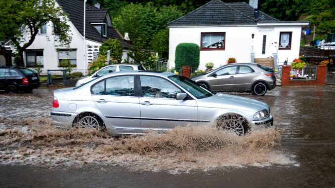 Unwetter in Hamburg Ein Auto fährt im Hamburger Stadtteil Lohbrügge über eine von Starkregen überfluteten Straße. (Archivbild)