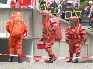 Feuerwehrleute betreten in Spezialanzügen die Tiefgarage.