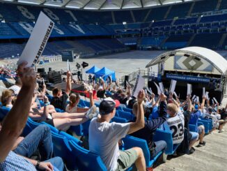 HSV-Fans halten Stimmzettel bei der Mitgliederversammlung des Clubs hoch.
