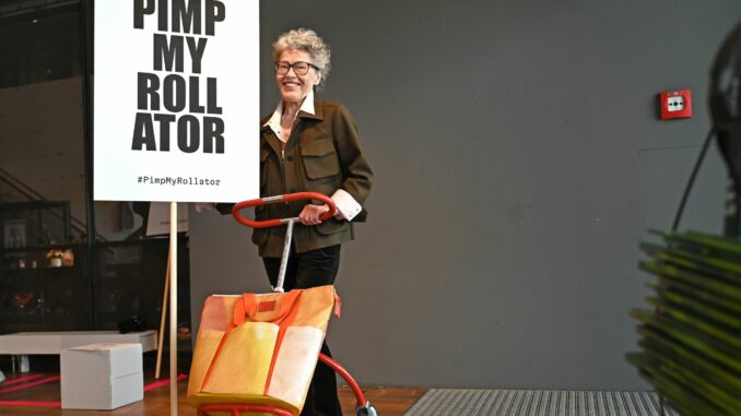 Initiative «Pimp my Rollator» in der Hafen City Elke Jensen mit einem gestalteten Rollator und einem Schild mit der Aufschrift «Pimp my Rollator» im Design Zentrum Hamburg.