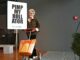 Elke Jensen mit einem gestalteten Rollator und einem Schild mit der Aufschrift «Pimp my Rollator» im Design Zentrum Hamburg.