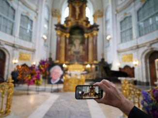 Ein Besucher macht zu Beginn der Trauerfeier ein Foto mit einem Smartphone.