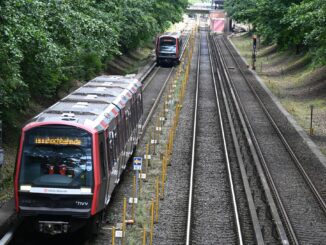 Zwei U-Bahnen der Hochbahn fahren in dichtem Abstand über die Gleise.