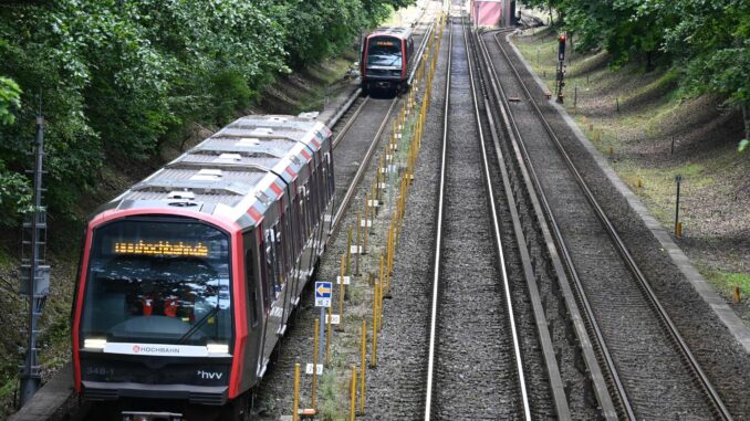 Zwei U-Bahnen der Hochbahn fahren in dichtem Abstand über die Gleise. 